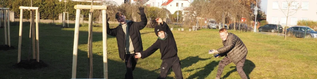 Kluci ze 4. oddílu ukazující směrem k nově vysazenému stromu na zahradě střediska.